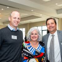 Group of 4 event attendees standing together, posing for camera and smiling